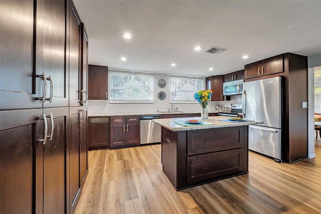 kitchen featuring light wood finished floors, appliances with stainless steel finishes, a sink, and visible vents