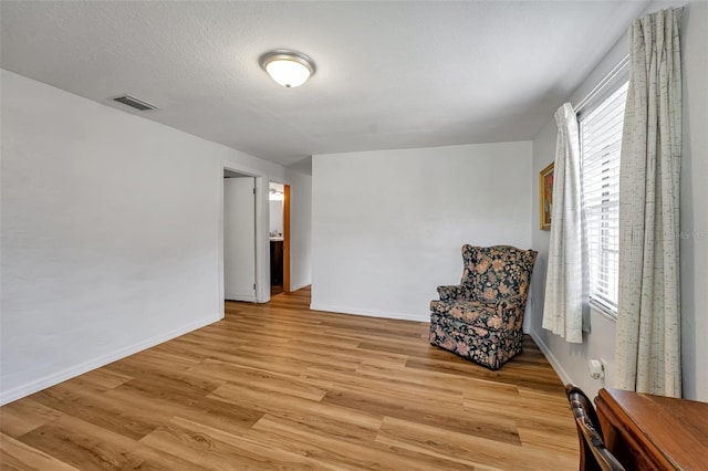 unfurnished room with visible vents, light wood-style flooring, baseboards, and a textured ceiling