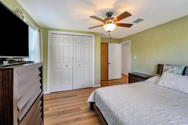 bedroom with light wood finished floors, visible vents, baseboards, a ceiling fan, and a closet