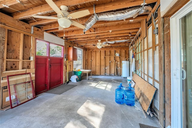 misc room with a garage, water heater, a ceiling fan, and unfinished concrete floors