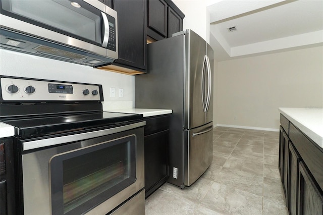 kitchen with appliances with stainless steel finishes, light countertops, visible vents, and baseboards