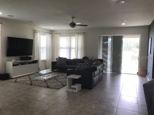 living area with tile patterned flooring, plenty of natural light, and ceiling fan