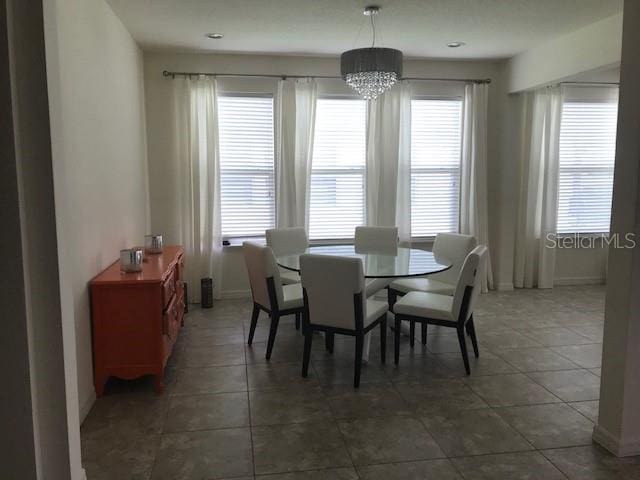 tiled dining space featuring an inviting chandelier and baseboards