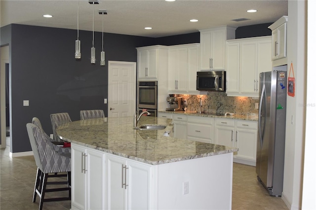 kitchen with stainless steel appliances, white cabinets, a sink, and tasteful backsplash