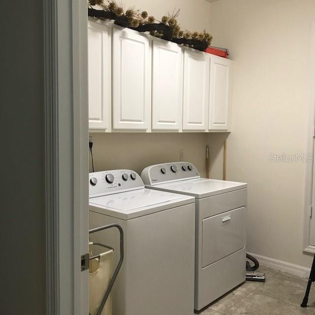 clothes washing area featuring cabinet space, baseboards, and washer and dryer