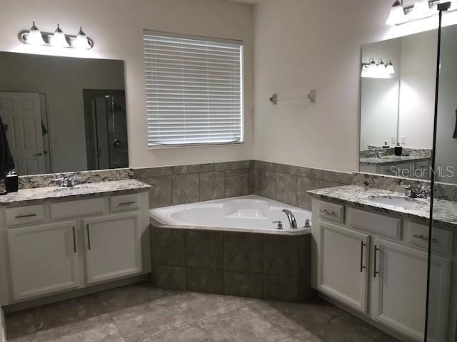 bathroom featuring two vanities, a sink, a bath, and a shower stall