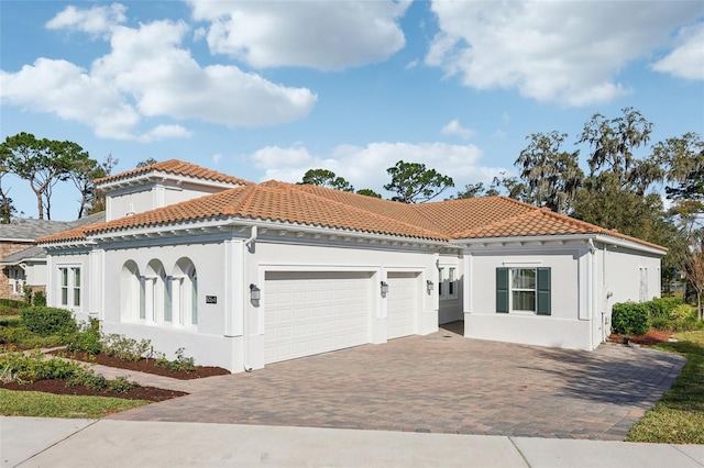 mediterranean / spanish home featuring a garage, driveway, a tile roof, and stucco siding