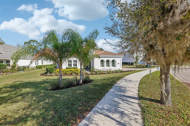 exterior space featuring a tiled roof, a front lawn, and stucco siding