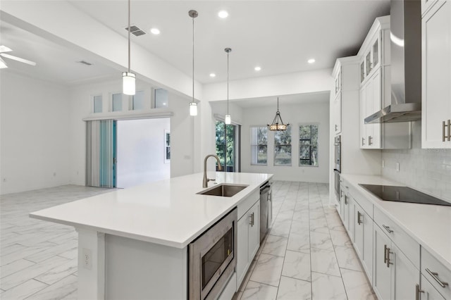 kitchen with marble finish floor, stainless steel appliances, wall chimney range hood, a sink, and recessed lighting