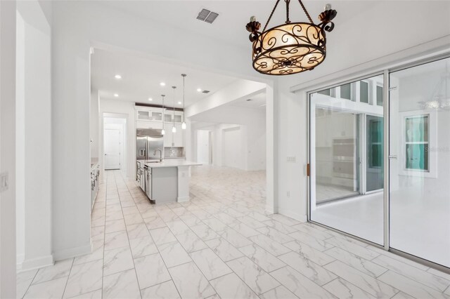 kitchen featuring visible vents, white cabinets, marble finish floor, light countertops, and stainless steel refrigerator with ice dispenser