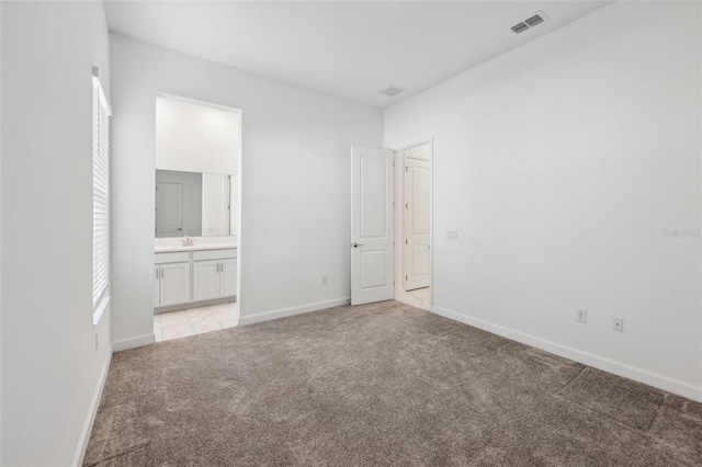 unfurnished bedroom with light carpet, baseboards, visible vents, and a sink