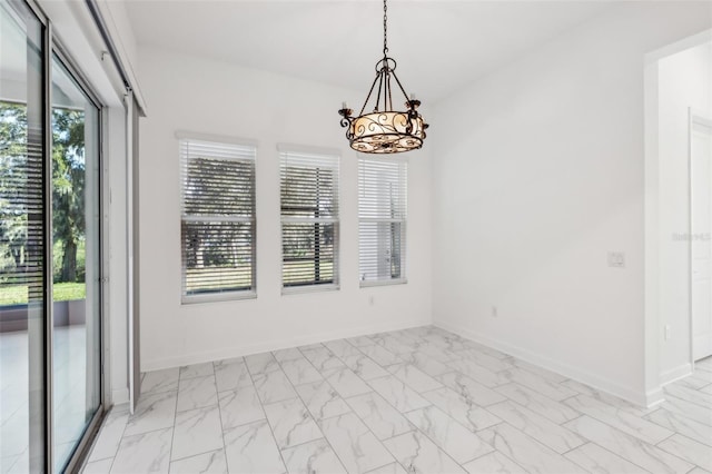 unfurnished room with a healthy amount of sunlight, marble finish floor, baseboards, and a chandelier