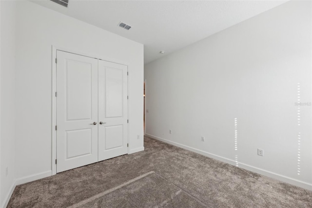 unfurnished bedroom with a closet, carpet flooring, visible vents, and baseboards