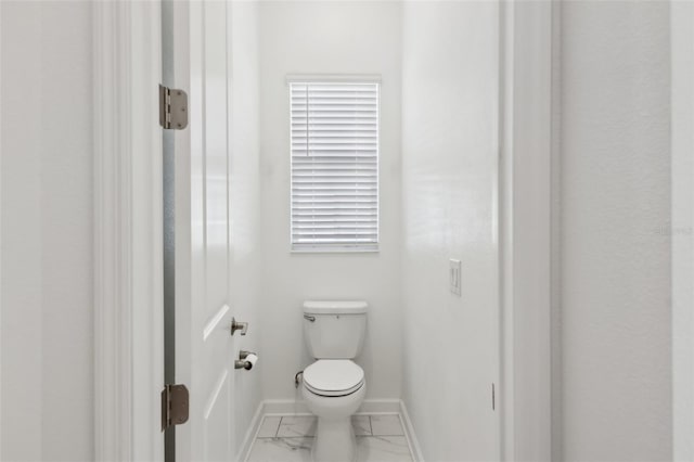 bathroom featuring marble finish floor, toilet, and baseboards