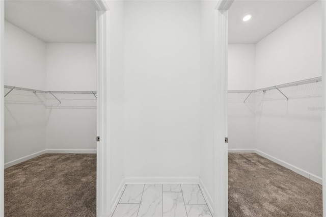 walk in closet with marble finish floor and light colored carpet