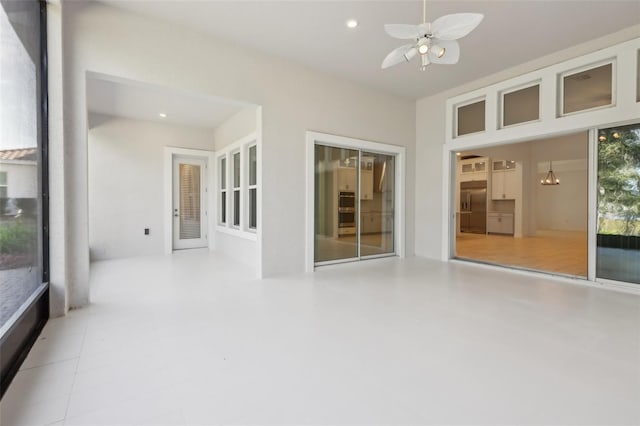 unfurnished sunroom featuring ceiling fan with notable chandelier