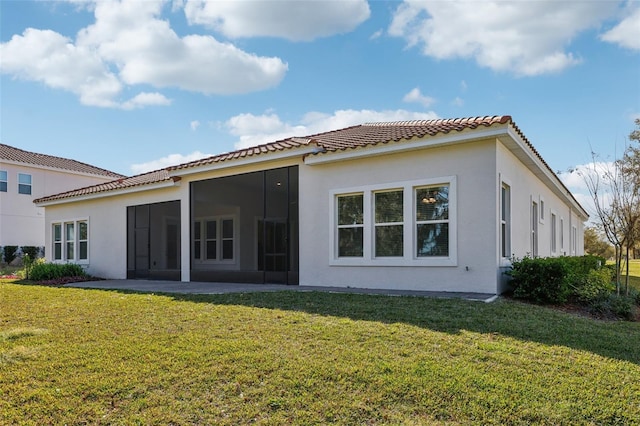 back of property with a sunroom, a lawn, and stucco siding