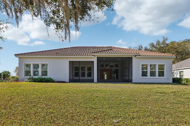 rear view of house featuring a tiled roof, a lawn, a sunroom, and stucco siding