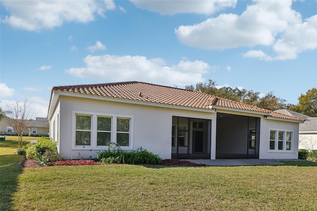 back of property featuring stucco siding, a tile roof, a sunroom, and a yard