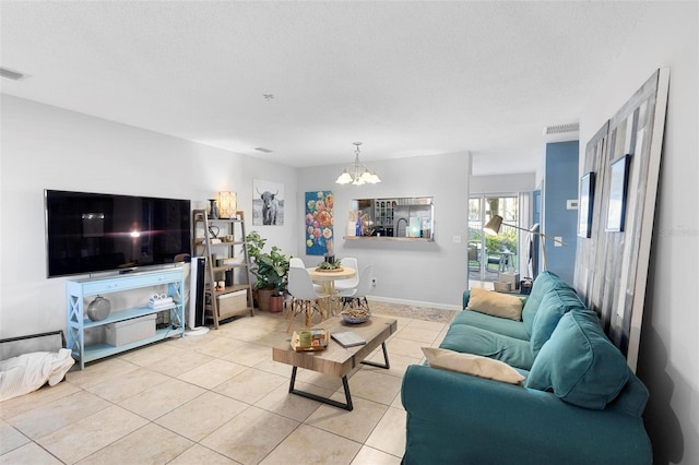 tiled living room featuring visible vents, a notable chandelier, a textured ceiling, and baseboards