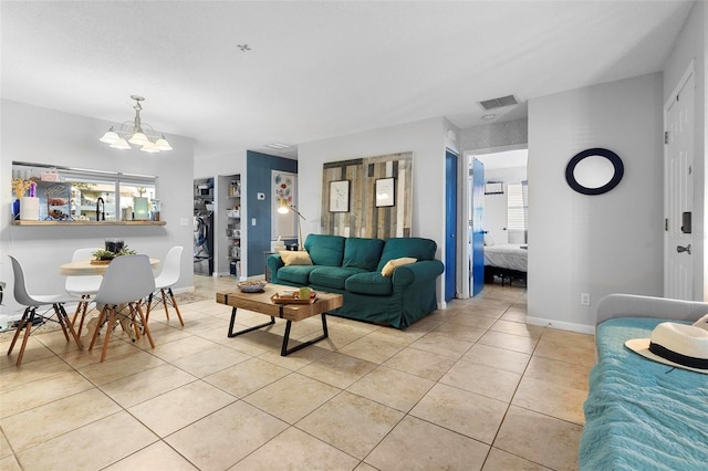 living area featuring visible vents, a notable chandelier, baseboards, and light tile patterned floors