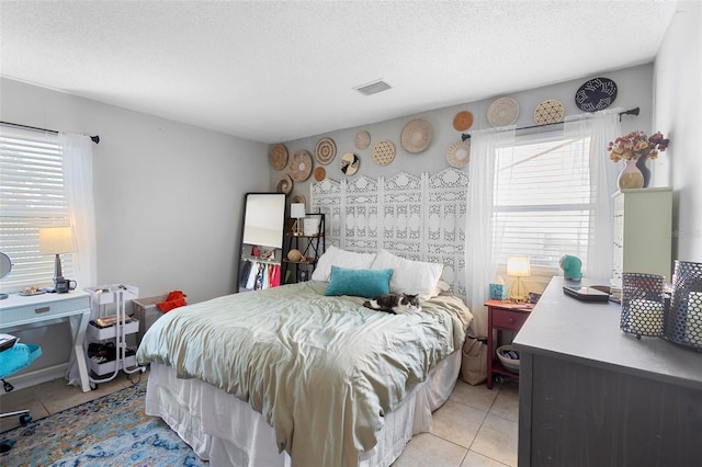 bedroom with light tile patterned floors, multiple windows, visible vents, and a textured ceiling