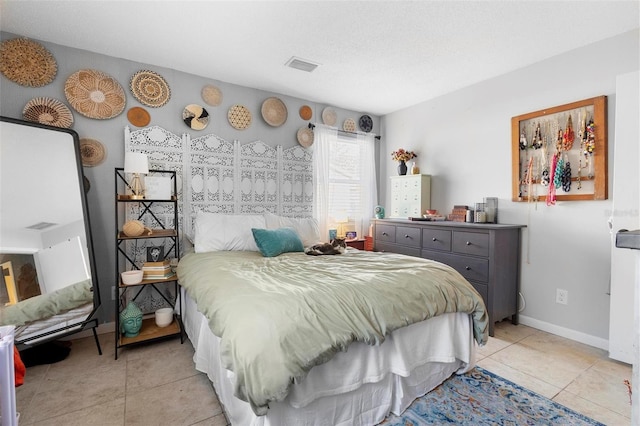 bedroom featuring baseboards, visible vents, a textured ceiling, and light tile patterned flooring