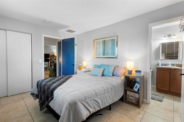 bedroom featuring light tile patterned floors, connected bathroom, a sink, visible vents, and a closet