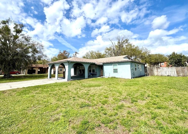 back of property with driveway, fence, a lawn, and stucco siding