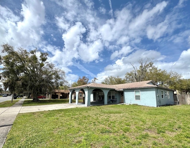 view of front of house with driveway, a front lawn, and stucco siding