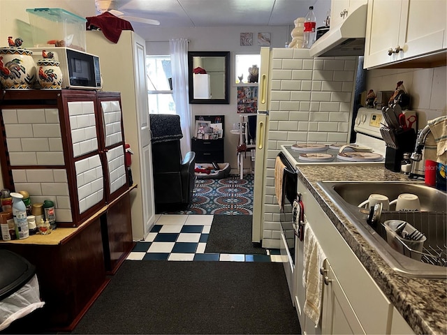 kitchen with under cabinet range hood, a sink, white cabinets, tile patterned floors, and electric range oven