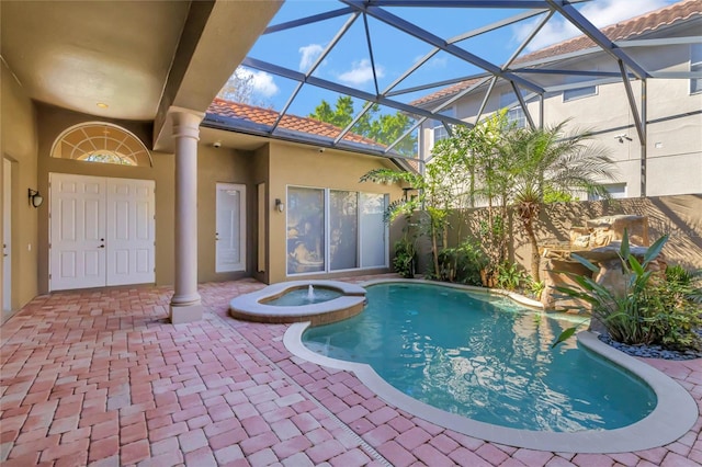 view of pool featuring glass enclosure, a pool with connected hot tub, and a patio area