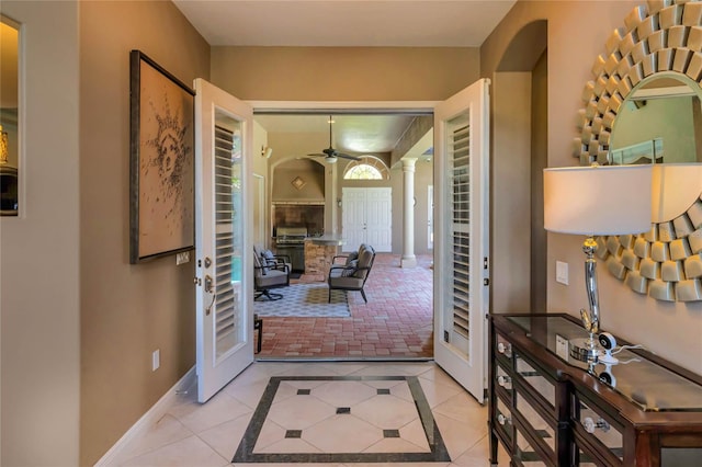 entryway with decorative columns, baseboards, a ceiling fan, and light tile patterned flooring