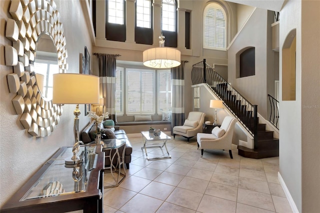 tiled living area with a high ceiling, stairs, and baseboards