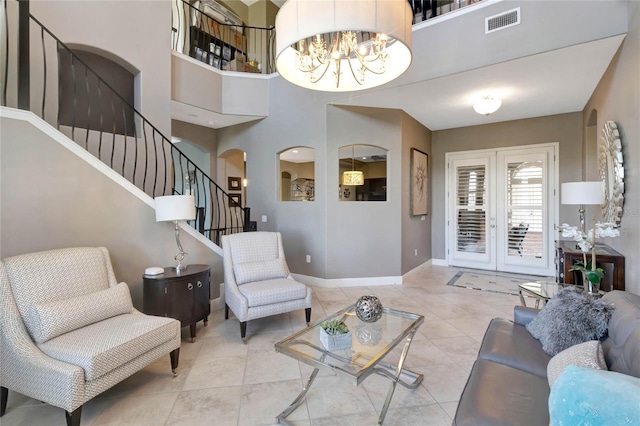 tiled living room with arched walkways, a notable chandelier, visible vents, baseboards, and stairs