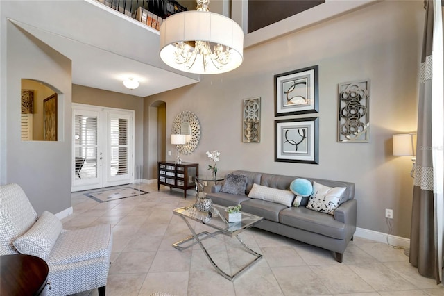 living area with arched walkways, a notable chandelier, baseboards, and light tile patterned floors