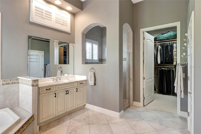 full bath with vanity, a spacious closet, a bath, tile patterned floors, and a stall shower