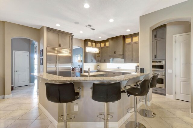 kitchen featuring light tile patterned floors, visible vents, light stone counters, and stainless steel appliances