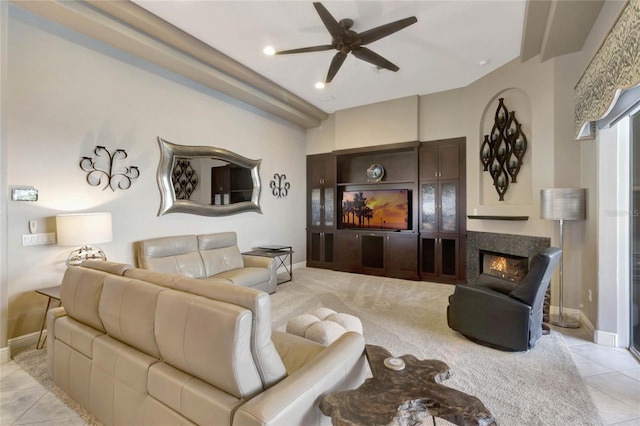 living room with light tile patterned floors, baseboards, a ceiling fan, light colored carpet, and a glass covered fireplace