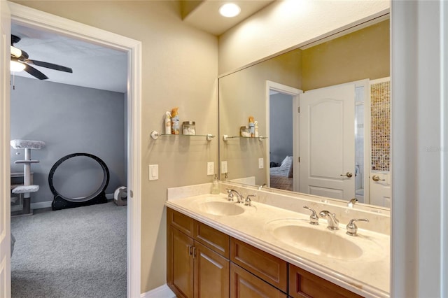 bathroom with ceiling fan, double vanity, a sink, and baseboards