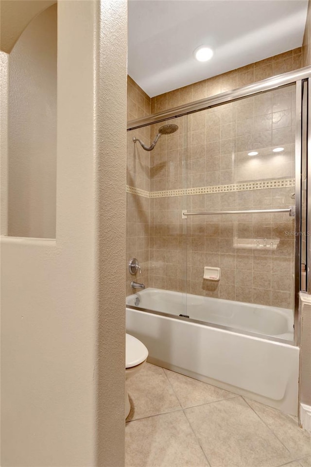 full bath with a textured wall, bath / shower combo with glass door, toilet, and tile patterned floors