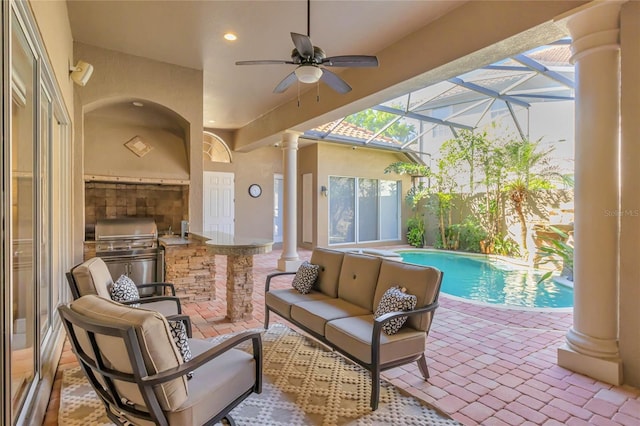 view of patio / terrace with a fenced in pool, outdoor lounge area, a ceiling fan, glass enclosure, and exterior kitchen