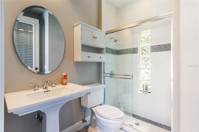 bathroom featuring toilet, a stall shower, and a sink