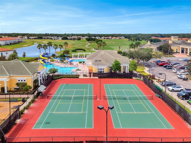 view of tennis court featuring a water view and fence