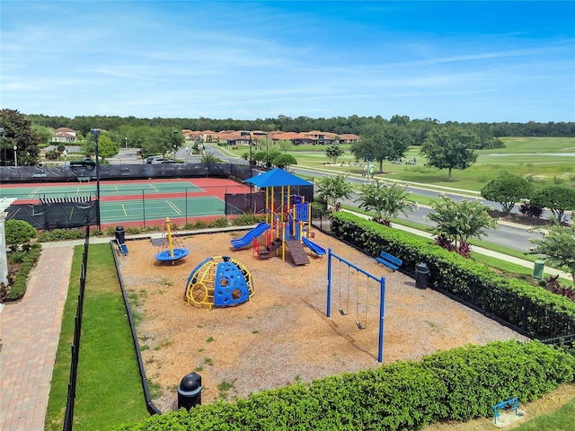 community play area featuring a tennis court and fence