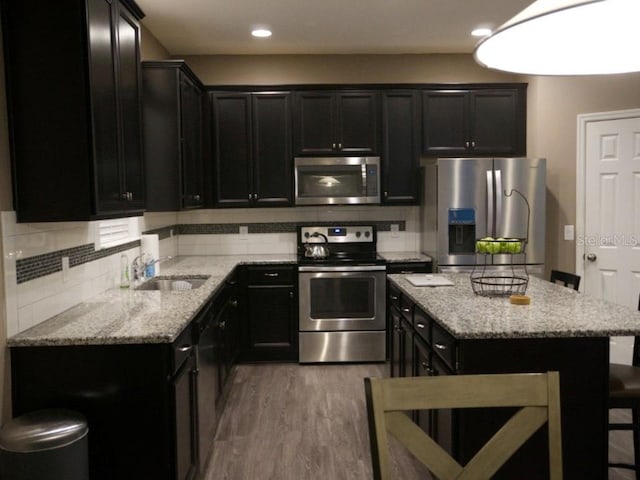 kitchen featuring backsplash, appliances with stainless steel finishes, light stone counters, and dark cabinetry