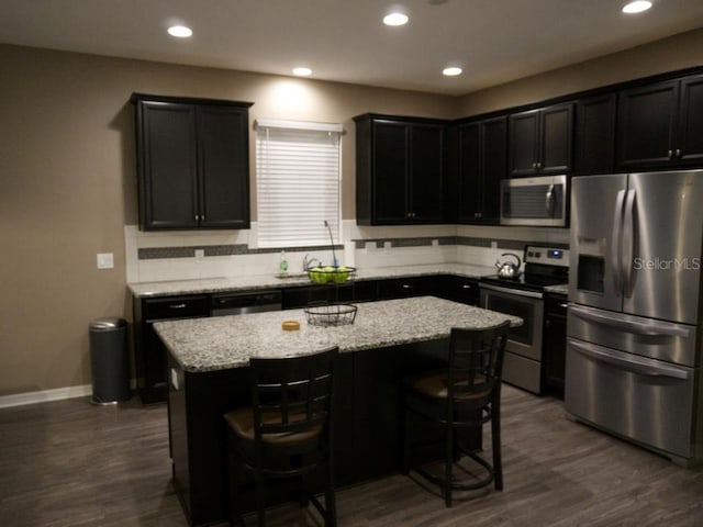 kitchen featuring dark wood-style floors, stainless steel appliances, tasteful backsplash, and a center island