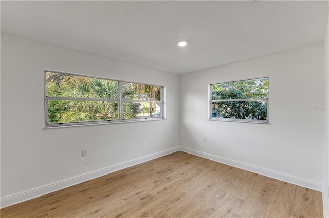 spare room featuring light wood-type flooring, baseboards, and recessed lighting