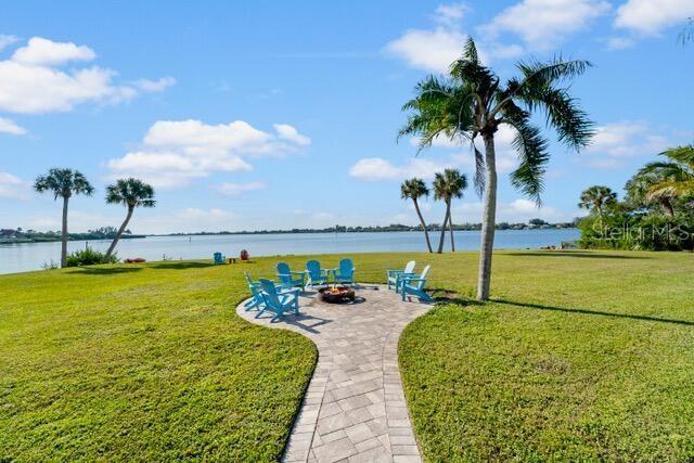 view of home's community with a fire pit, a lawn, and a water view