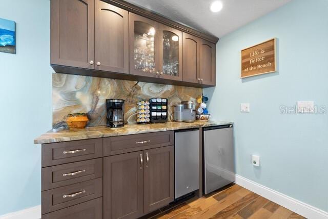 bar with refrigerator, a dry bar, backsplash, light wood-style floors, and baseboards